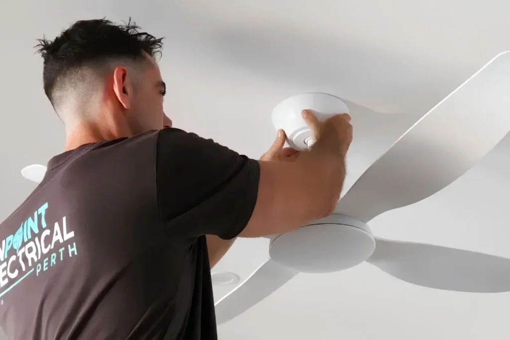 Electrician installing a ceiling fan in a Perth home